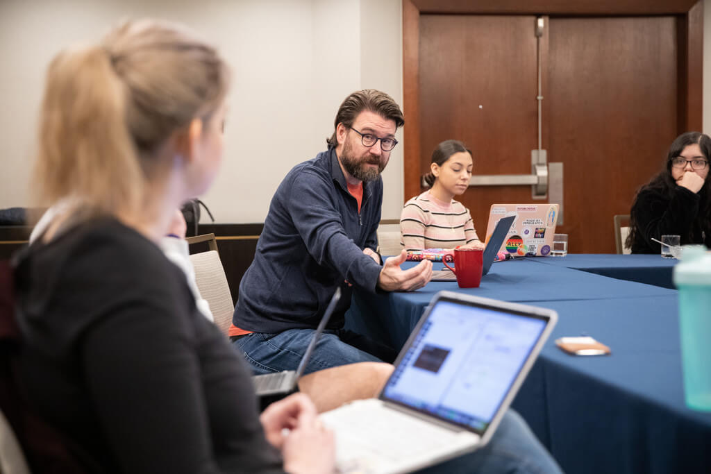 Bearded man with glasses sits at table