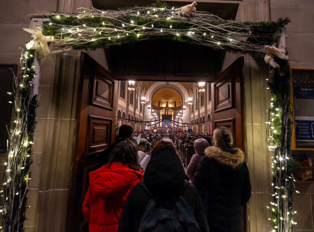 People stand at the decorated doorway of a church