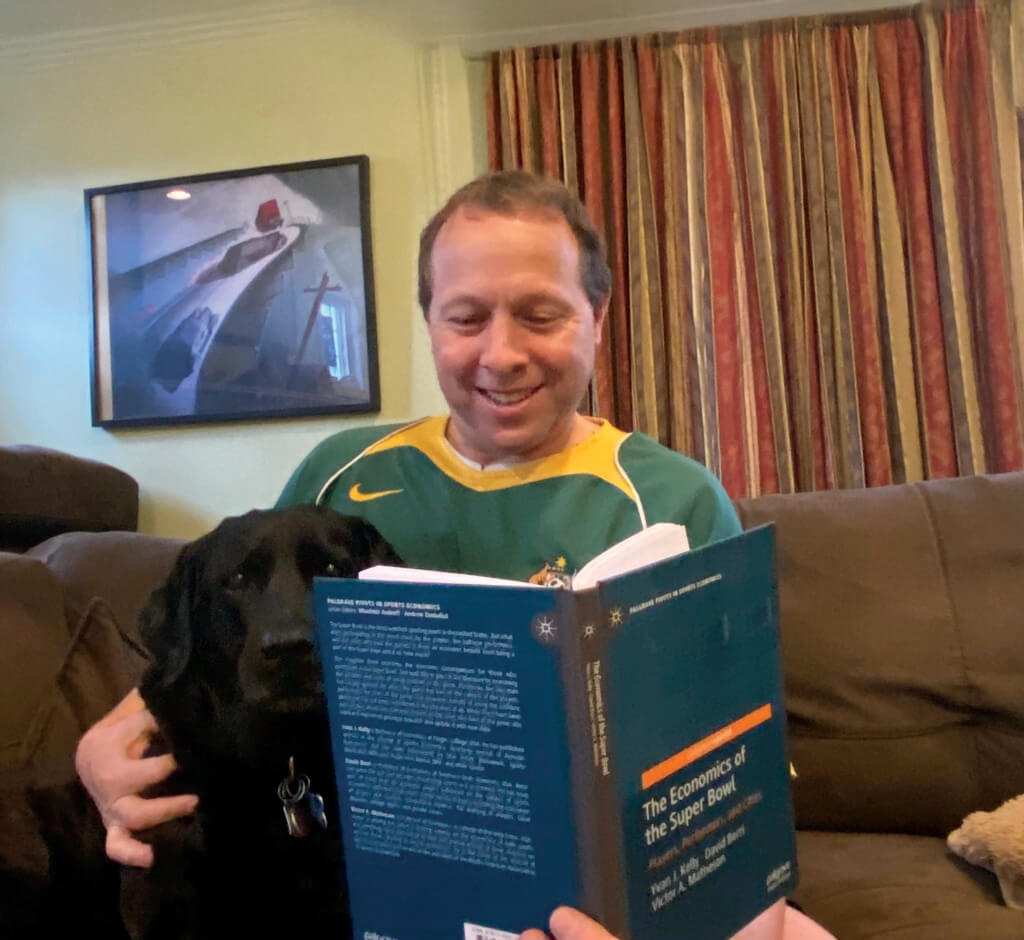 Man reads book next to dog