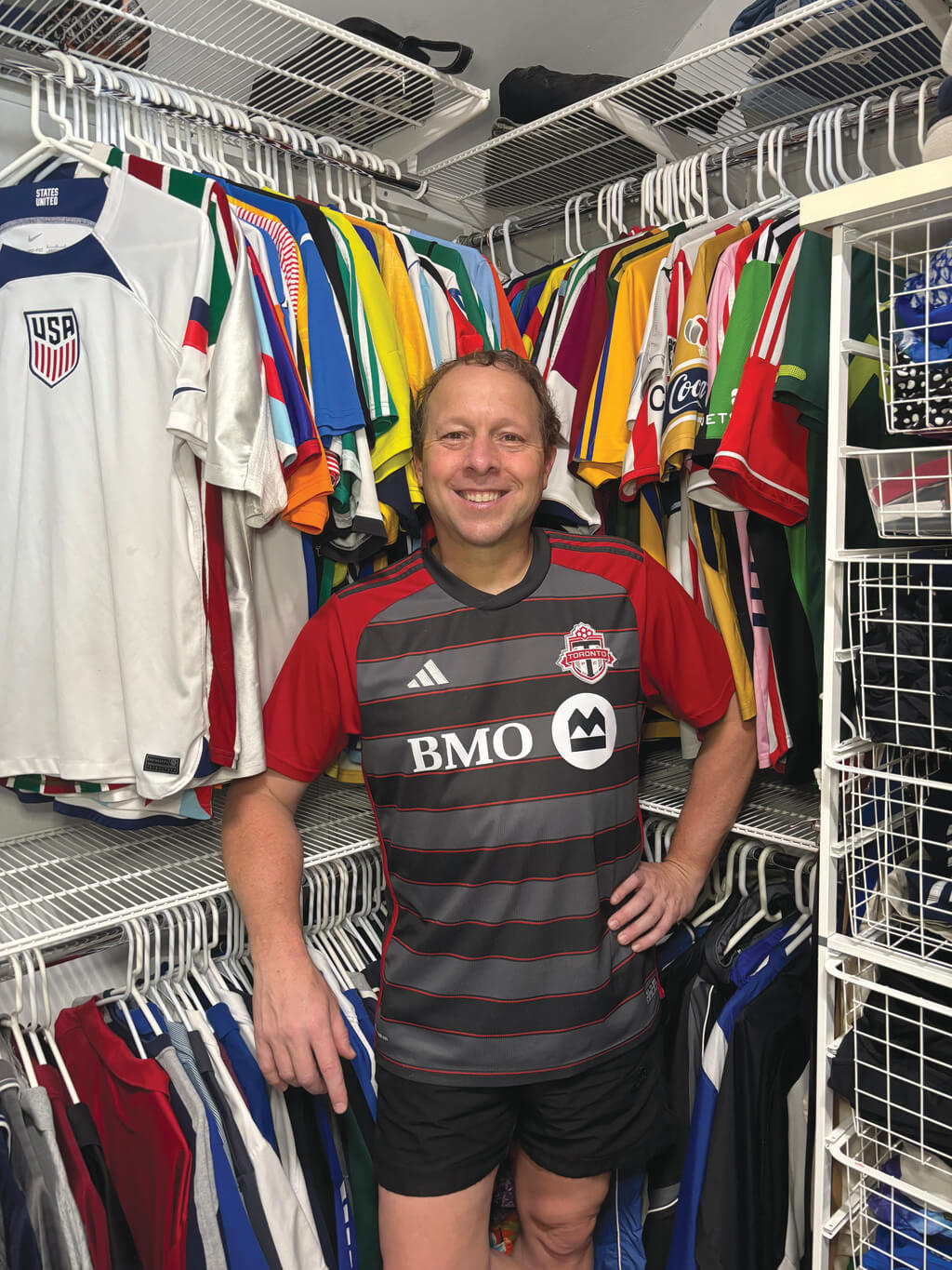 Man in soccer jersey stands in closet