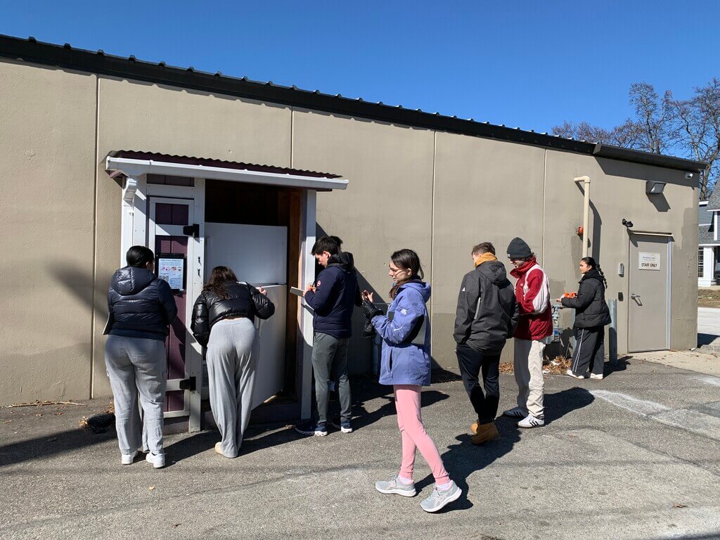A group of people look at an outdoor refrigerator