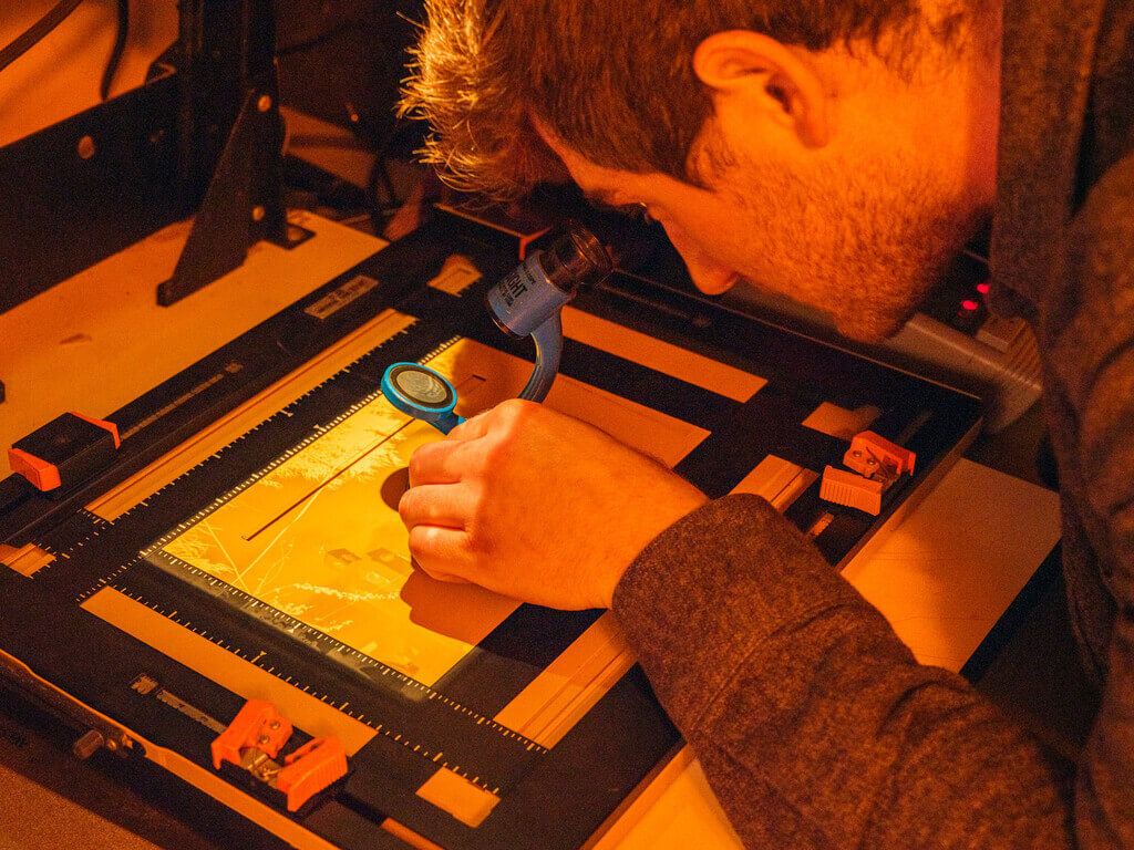 Photography student in darkroom looking at a print.