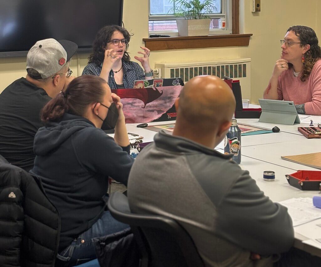 Four people sit at a table playing a game