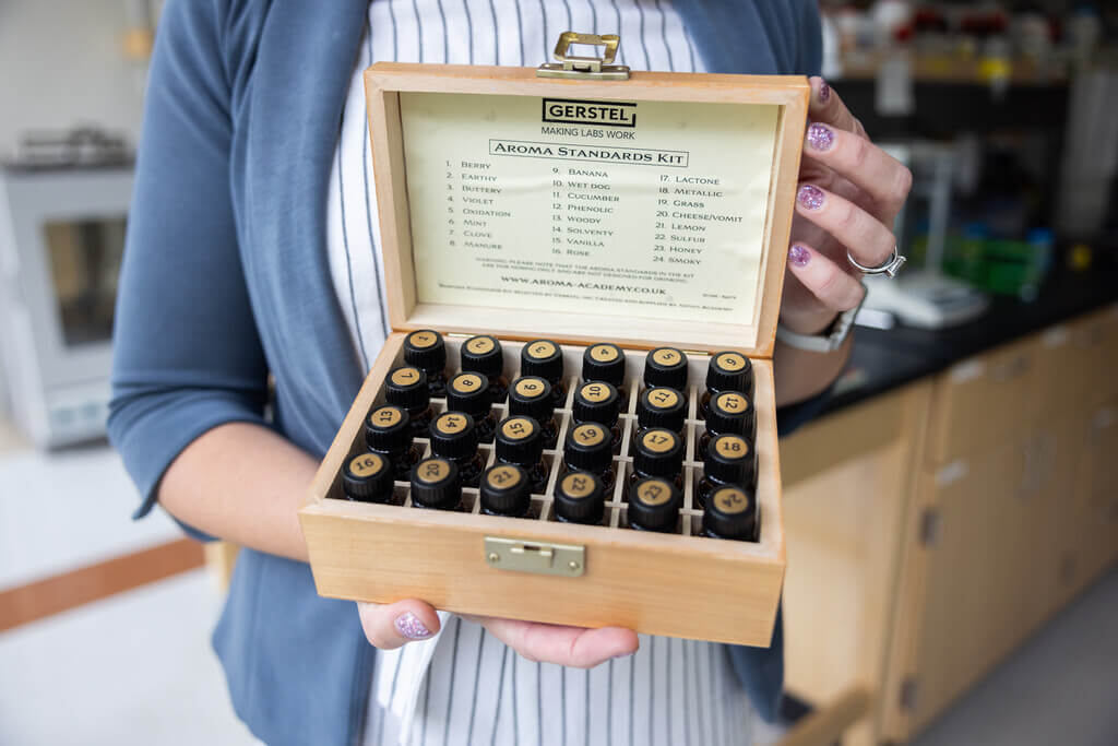 Woman holds a box of glass vials containing fragrances