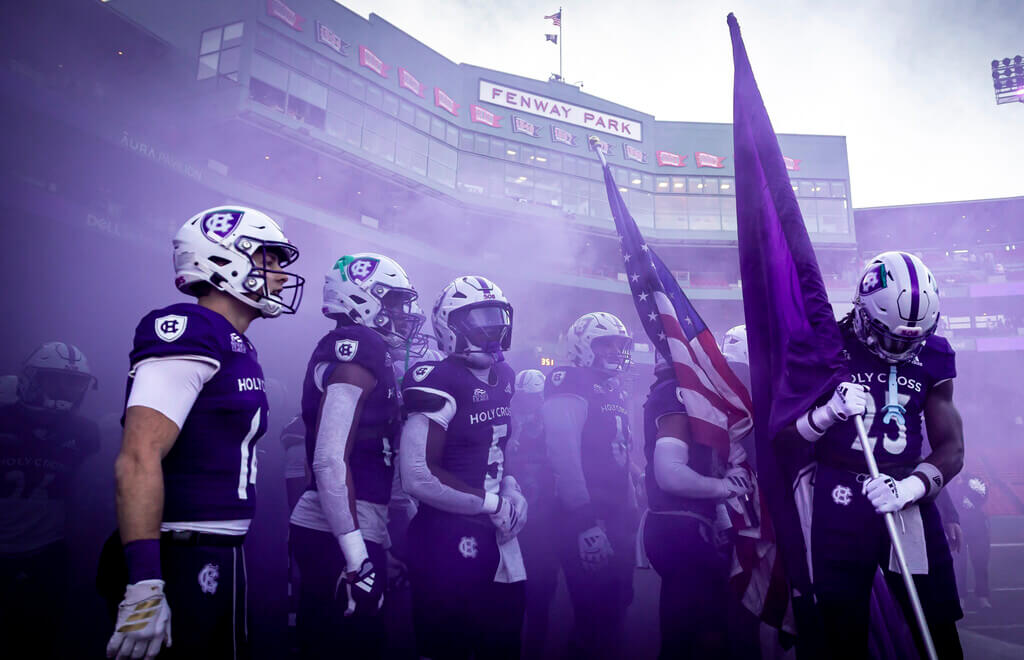 Football players on field amongst purple smoke