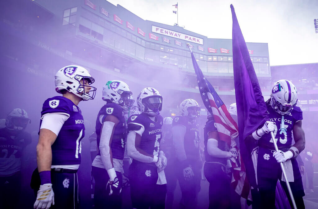 Holy Cross football players surrounded by purple smoke