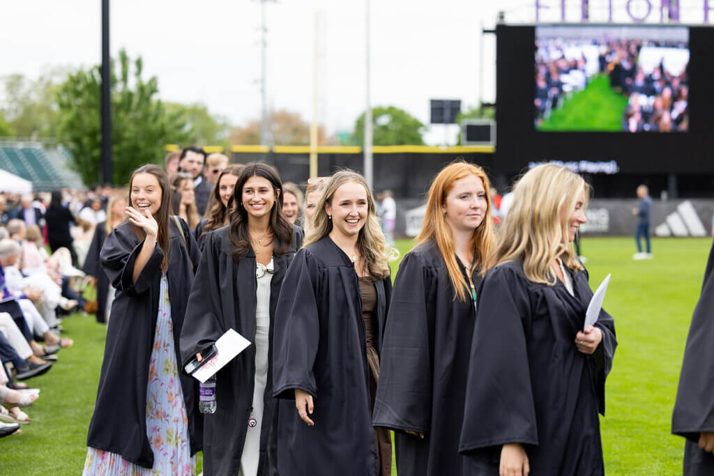 Graduates walking onto football field