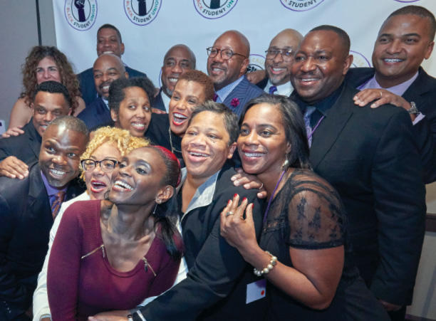 A group of people huddled together and smiling for a photo