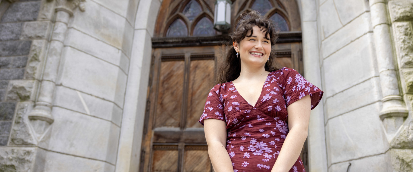 Smiling woman stands on church outside stairs