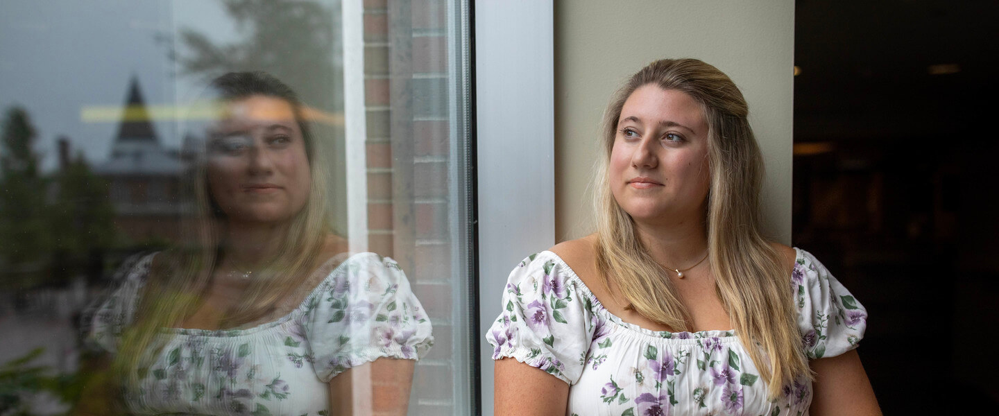 Woman sits on windowsill and looks out window