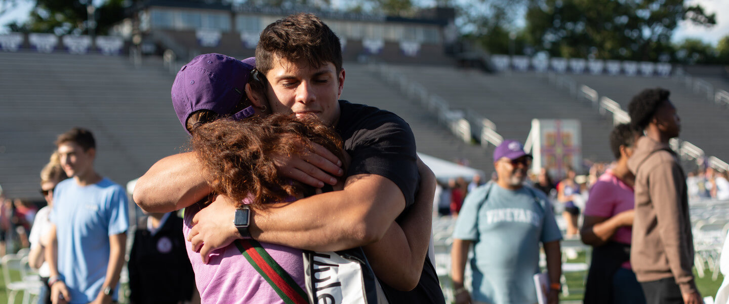 Mother and son embrace surrounded by others on a football field