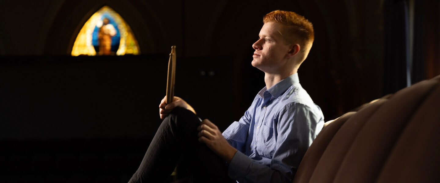 Side profile of man sitting holding drumsticks
