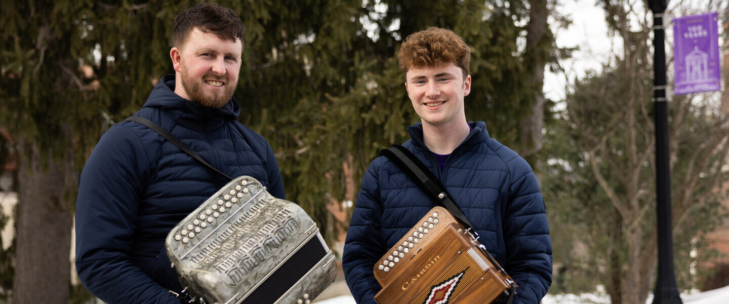 Two men holding button accordions in winter