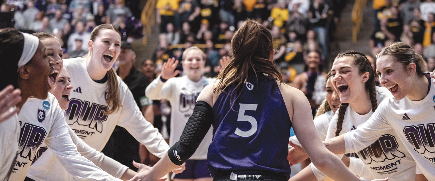 Women basketball players welcome teammate onto court.