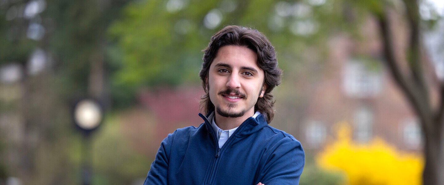 Man with beard stands with arms crossed