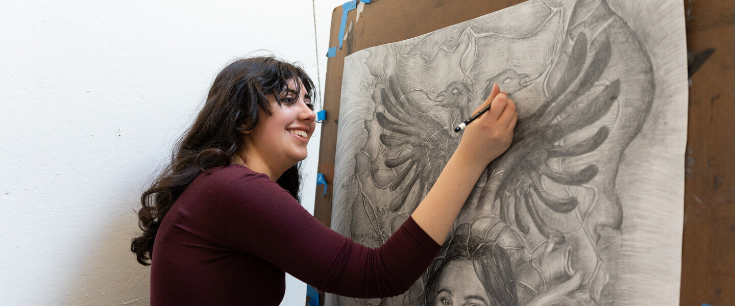 Sophie Sundaram working on a black and white drawing at an easel