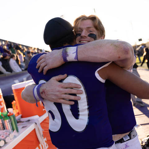 Two football players hug on sideline