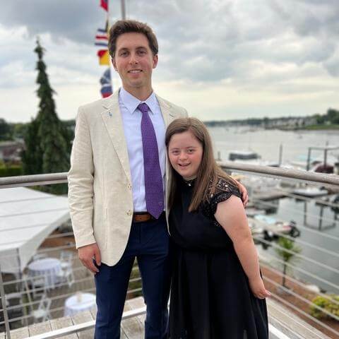 Young man standing with his sister, who has Down Syndrome, on a dock.