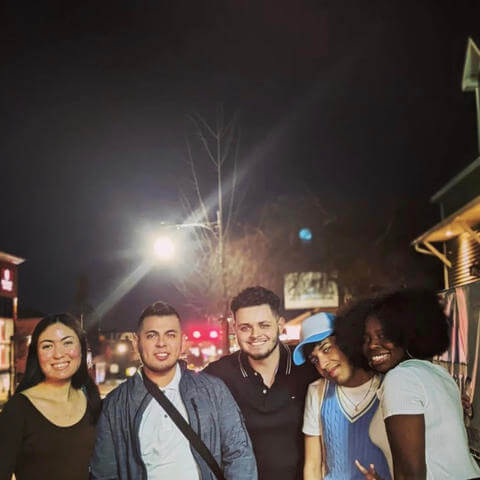 A group of young people pose for a photo at night