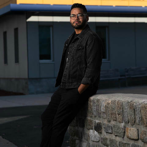 Bearded man leans agains a wall