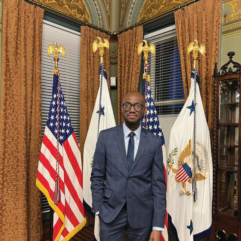 André Isaacs standing in front of flags in a presidential office