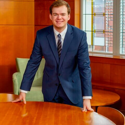 Young man in suit standing at table.