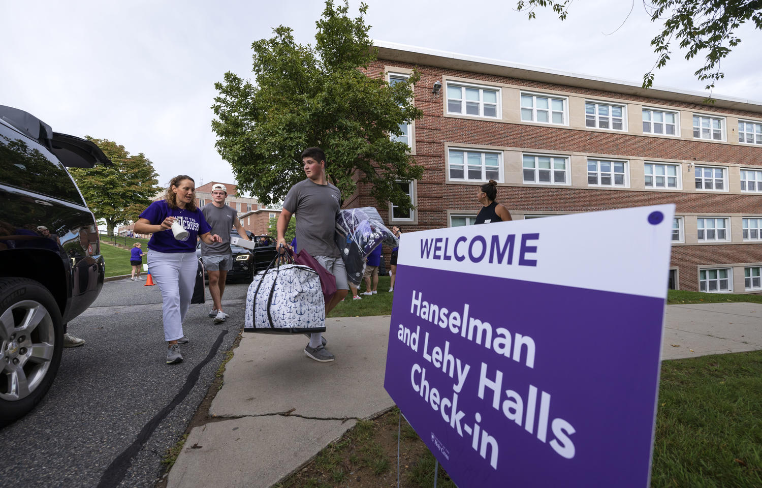 Students approaching a dorm with bags