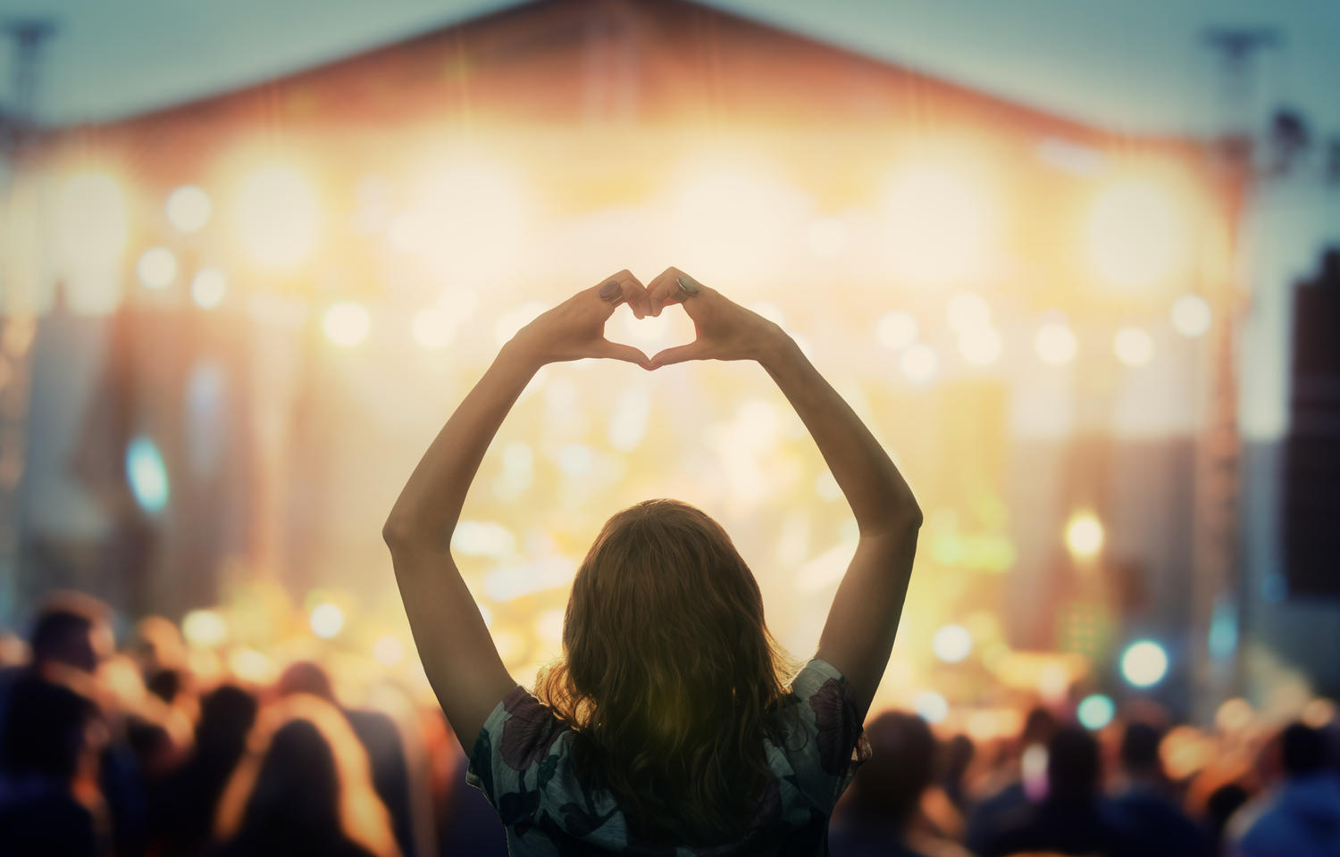 Girl making a heart-hand symbol for her favorite band. Photo credit: astrosystem