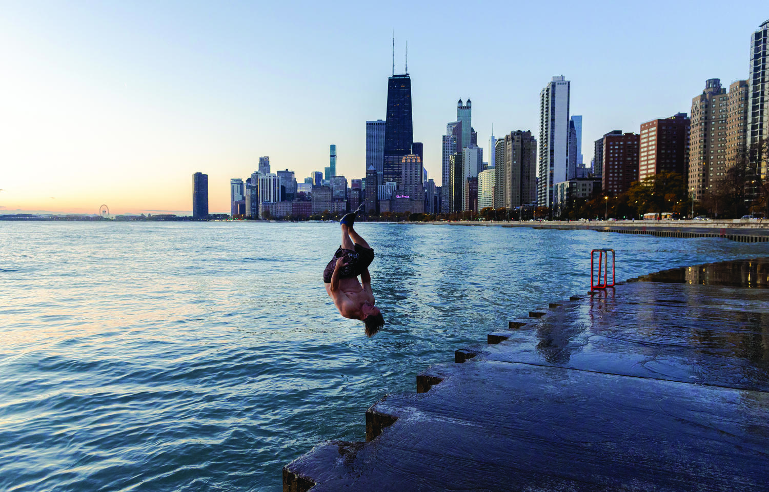 Man in bathing suit jumps into a lake at sunrise