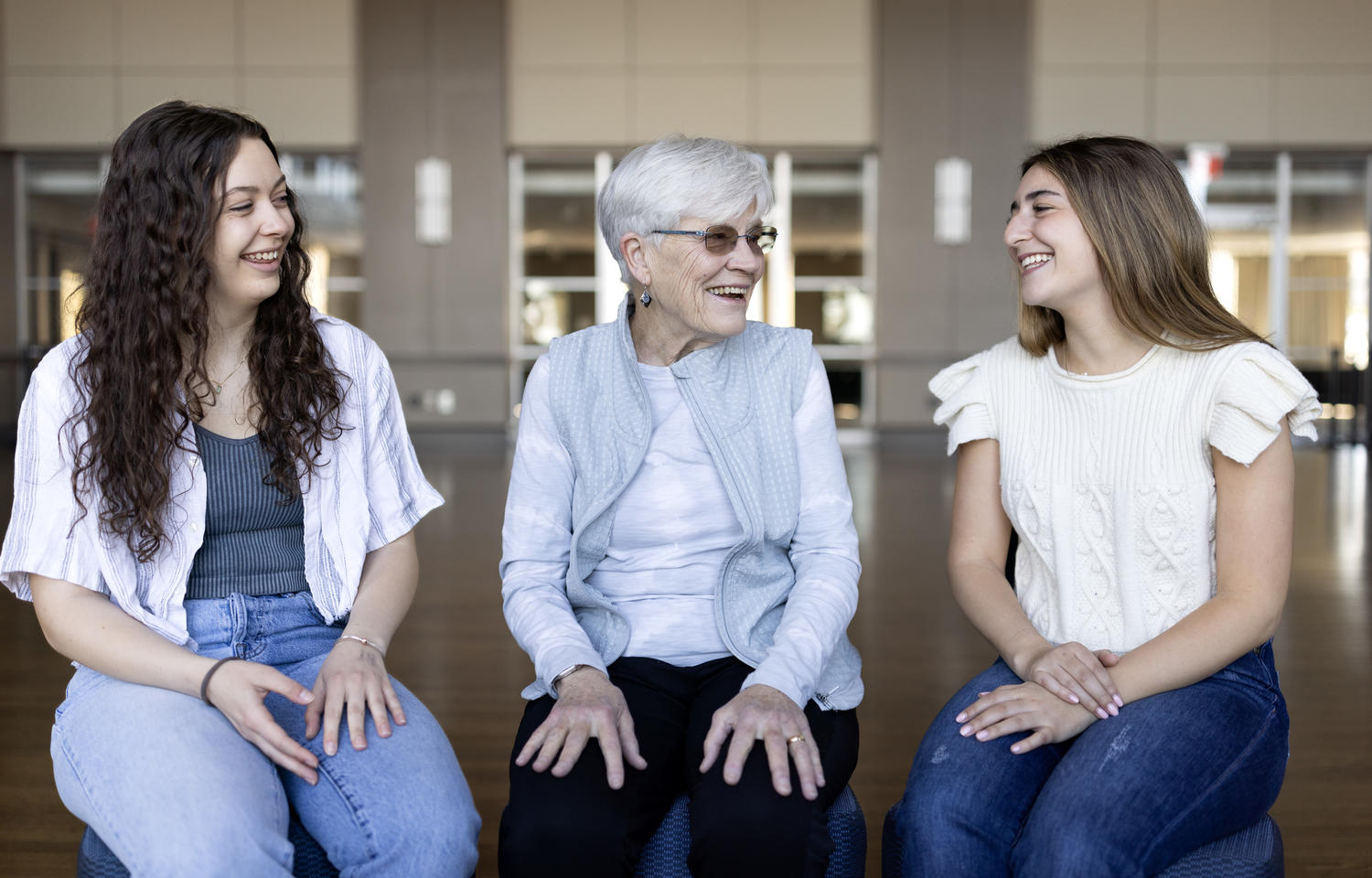 Two female graduating seniors talk with a female former professor.