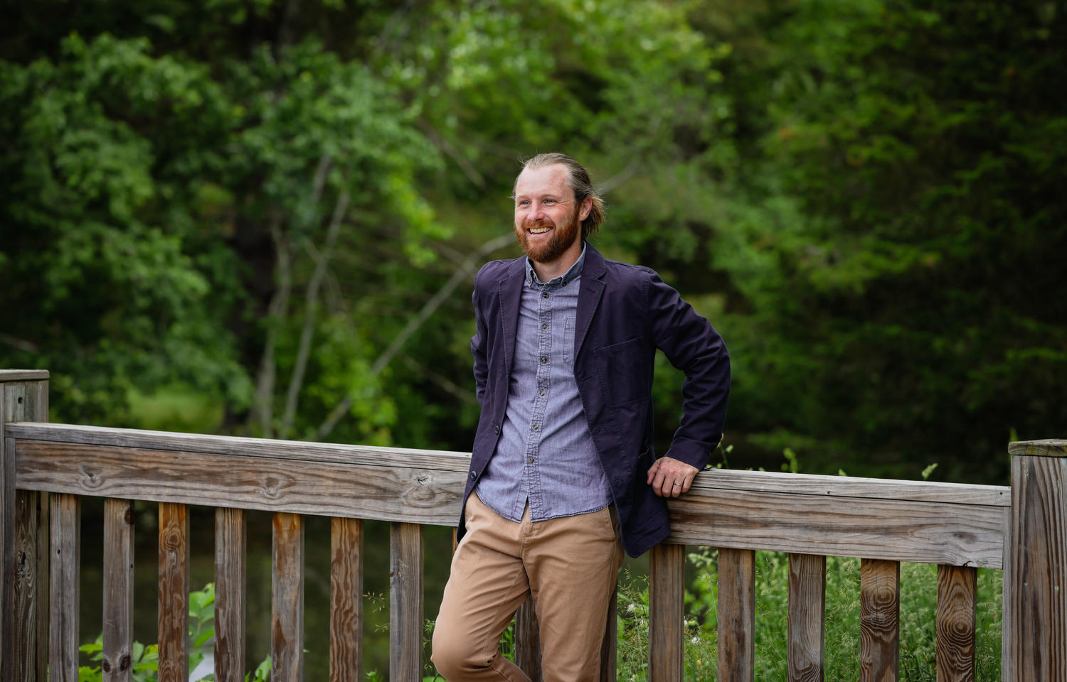 Bearded man leans against a bridge railing