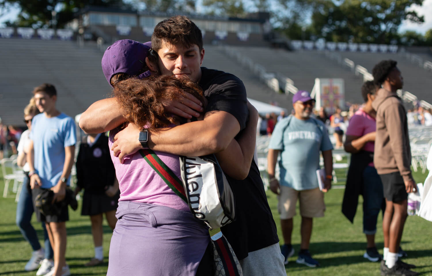 Mother and son embrace surrounded by others on a football field