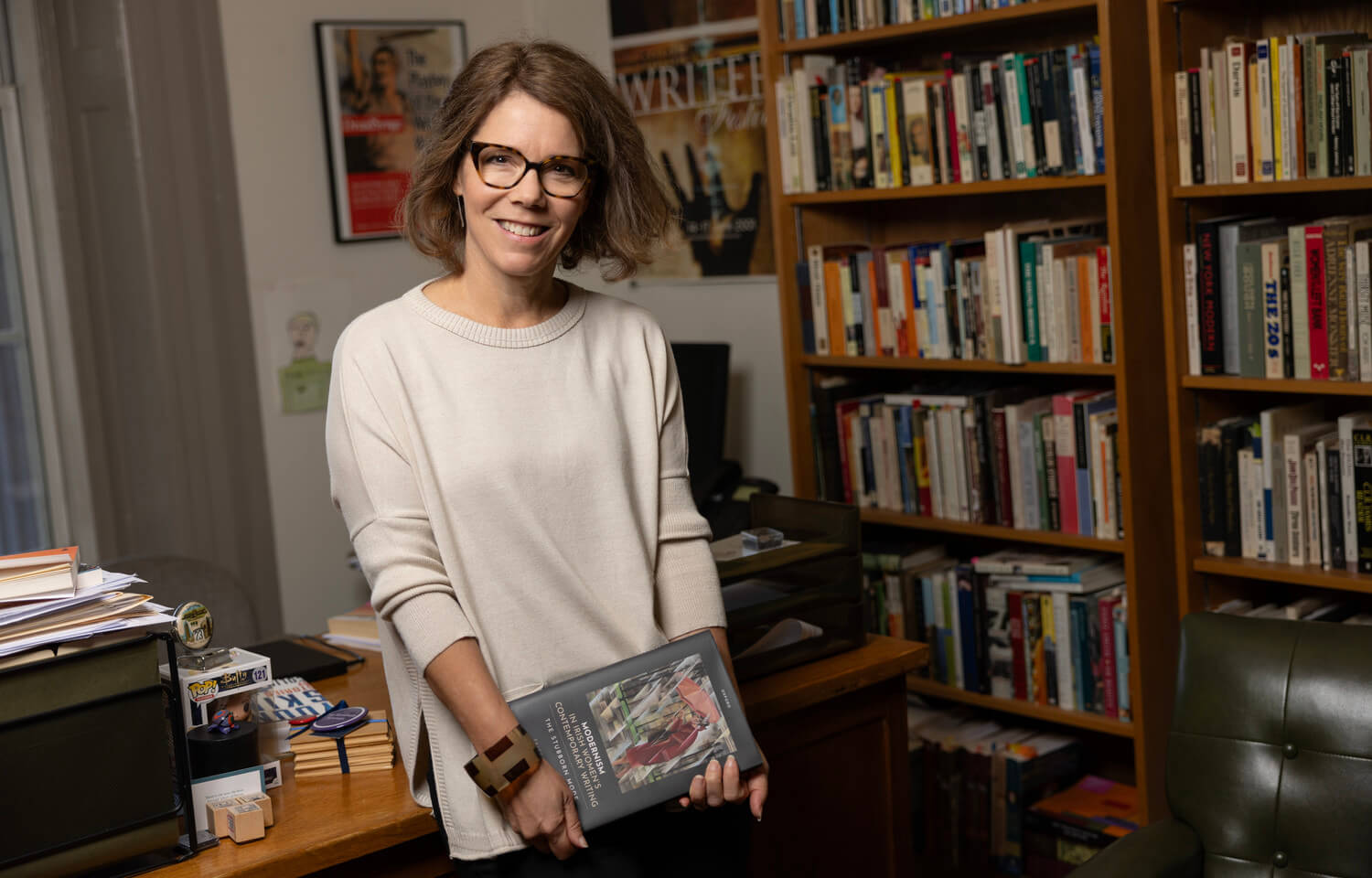 woman wearing glasses in office holding book
