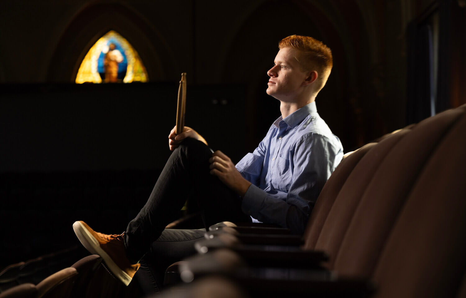 Side profile of man sitting holding drumsticks