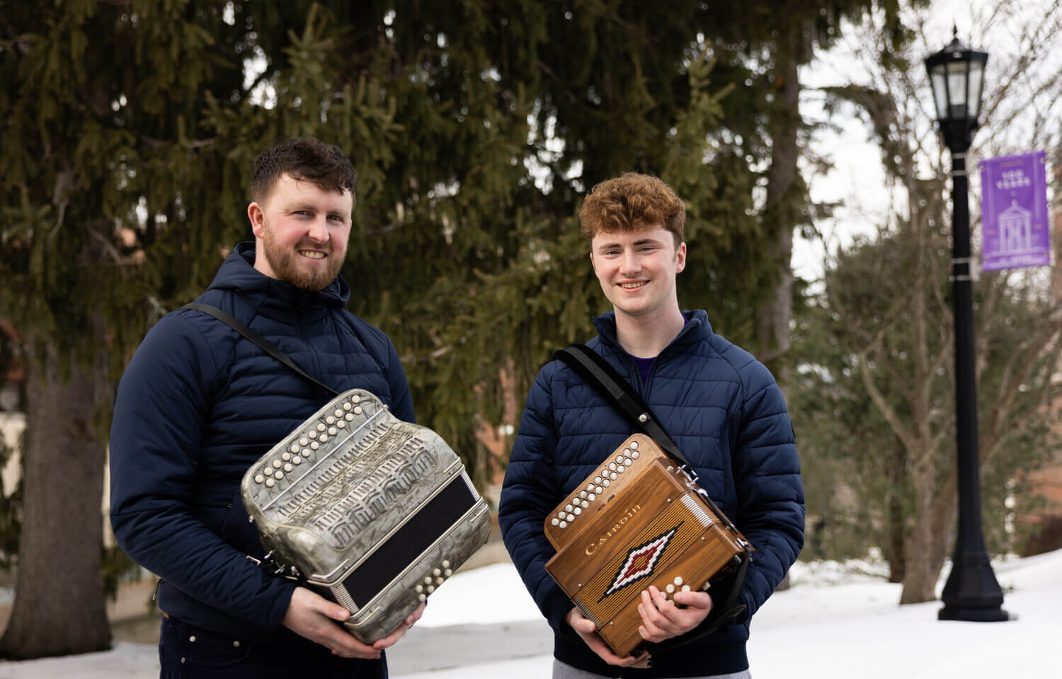 Two men holding button accordions in winter