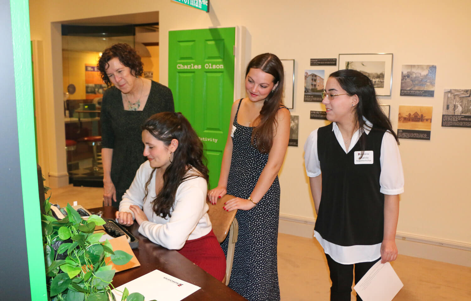 Women gathered around a woman typing