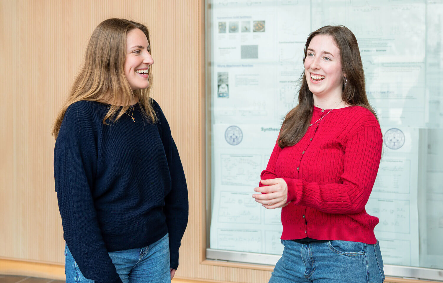 Two women in conversation in front of a whiteboard.