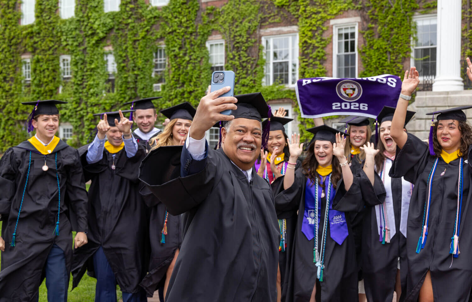 President Rougeau taking a selfie with graduates in front of Fenwick Hall