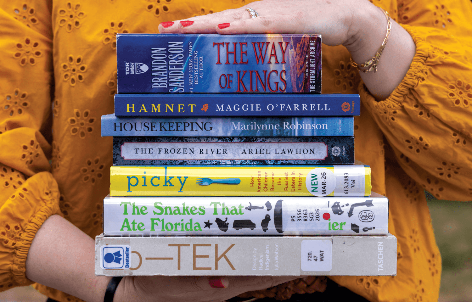 Hands holding a stack of books