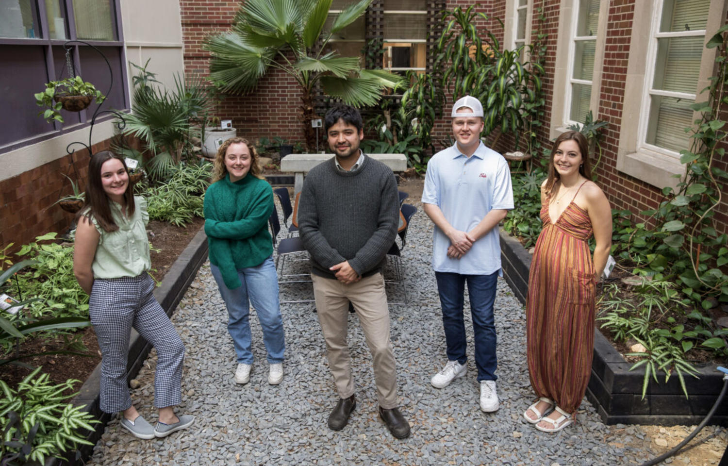 Four students stand with professor in the middle of botanic garden. 