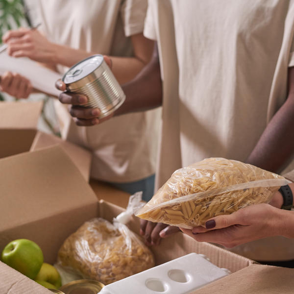People holding nonperishable foods to put in boxes for distribution.