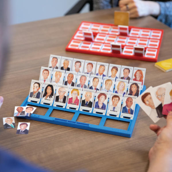 Two people play the game Guess Who where the faces have been switched for Democratic and Republican political figures