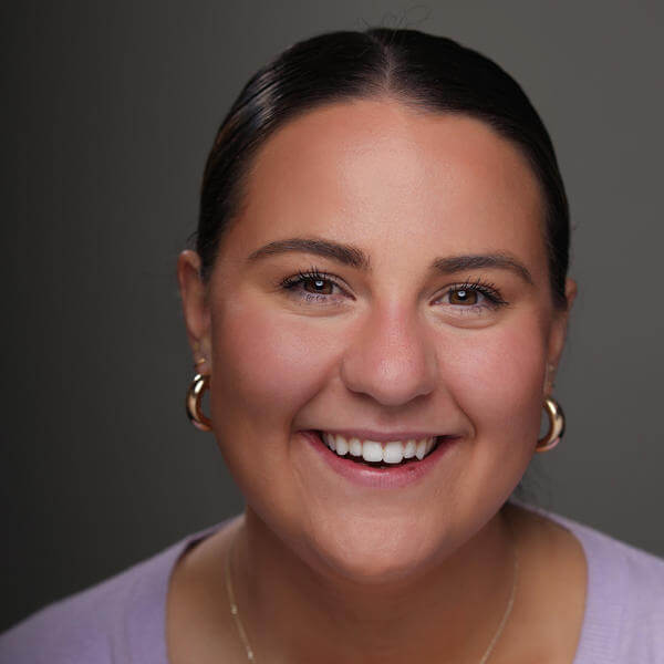 A portrait of a young woman with her hair tied back smiling 