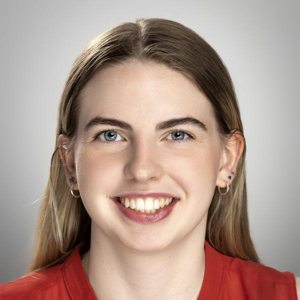 A young smiling young women in a red blouse with her hair pulled back behind her neck