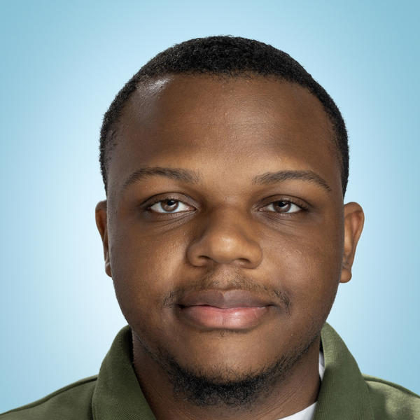 A young man smiles wearing a collard shirt 