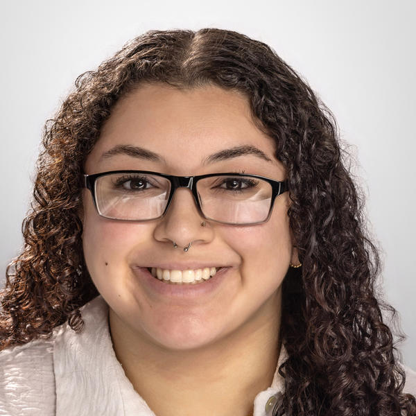 A smiling young woman with glasses and curly hair