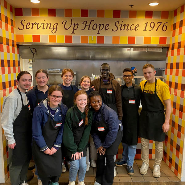 Group of college students volunteering at a soup kitchen.