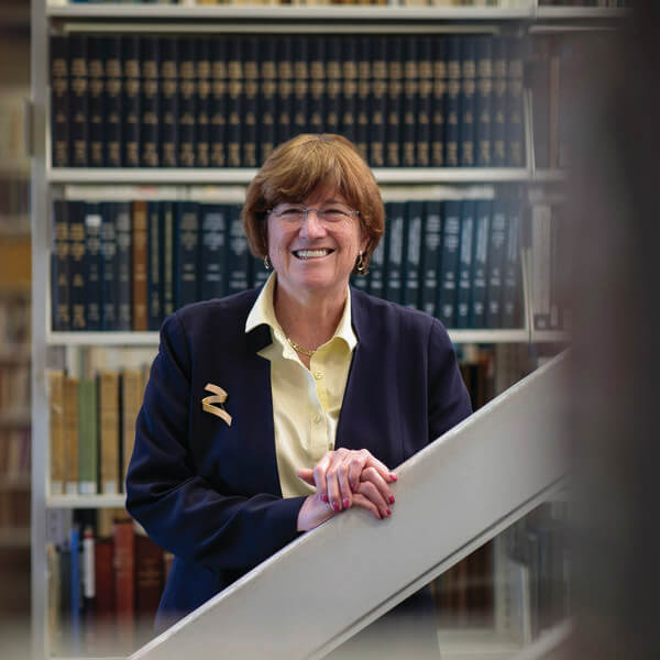 Smiling woman stands near a shelf of books