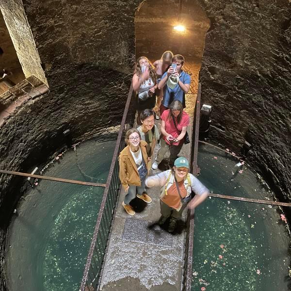 People stand on a bridge extending across the bottom of a giant well.