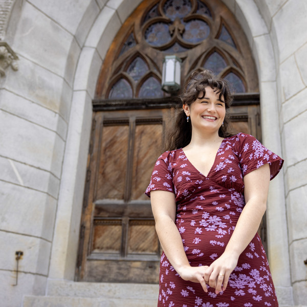 Smiling woman stands on church outside stairs